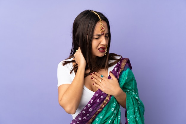 Joven india en pared púrpura con dolor de cuello