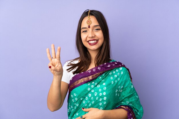 Foto joven india en pared púrpura feliz y contando tres con los dedos