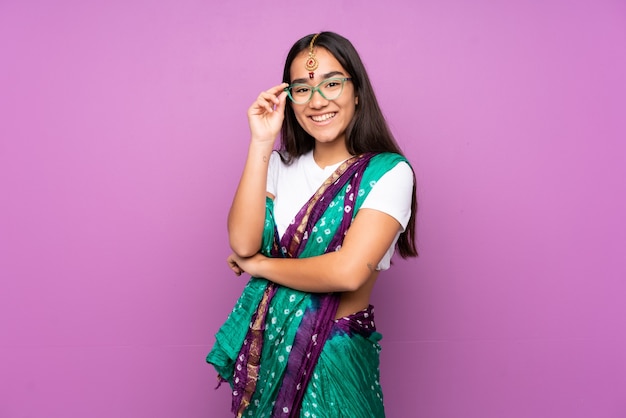 Joven india con sari sobre fondo aislado con gafas y feliz