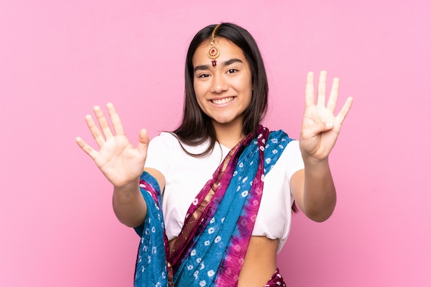 Joven india con sari sobre pared contando nueve con los dedos