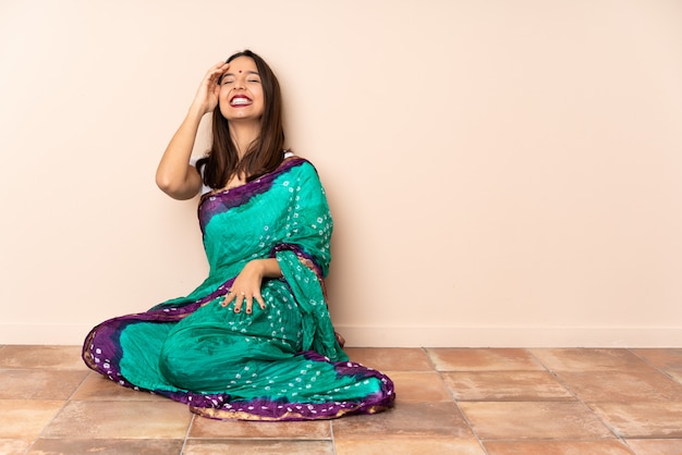 Joven india sentada en el suelo sonriendo mucho