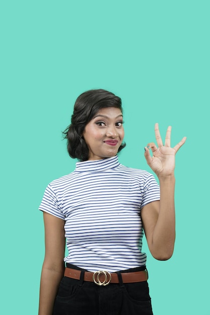 Foto una joven india sonriente y confiada muestra un signo de estar bien y un guiño dice que no hay problema, un buen gesto de acuerdo