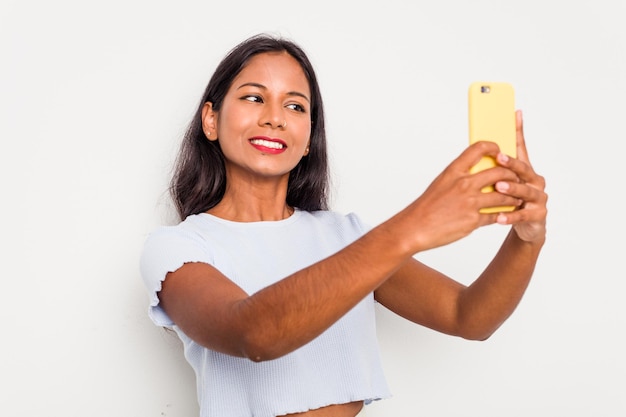 Joven india a través de teléfono móvil aislado sobre fondo blanco.