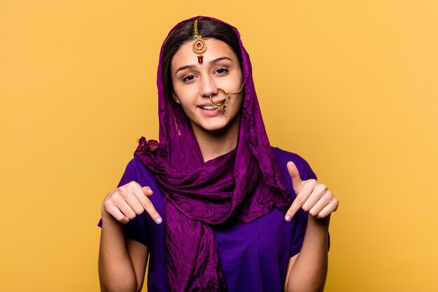 Joven india vistiendo un sari tradicional ropa aislado en amarillo apunta hacia abajo con los dedos, sentimiento positivo.