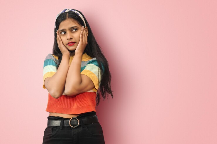 Joven indio asiático soñador se preguntó bastante glamorosa chica alegre posando aislada con las palmas en la cara mirando la esquina superior derecha complacida Concepto de moda y estilo de vida de belleza Mock up copy space