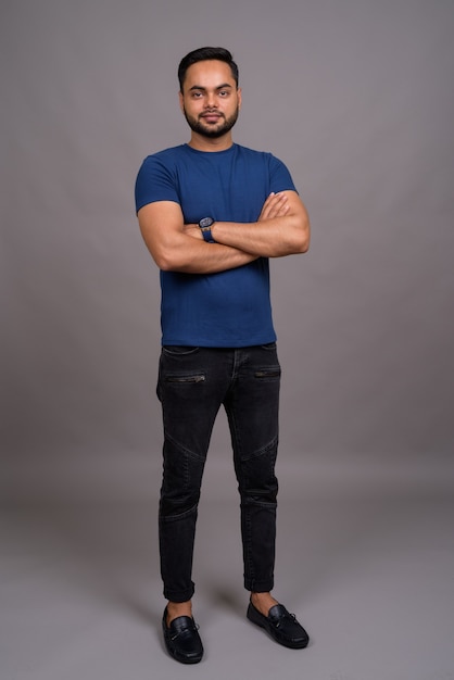 Foto joven indio barbudo contra la pared gris