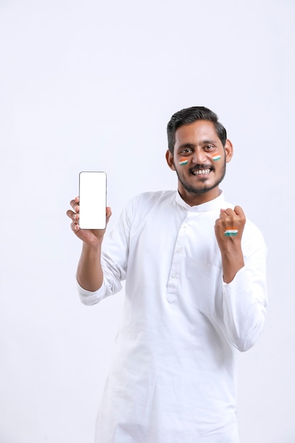 Joven indio celebrando el día de la independencia y mostrando el teléfono inteligente.