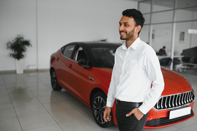 Un joven indio elige un auto nuevo en un concesionario de autos