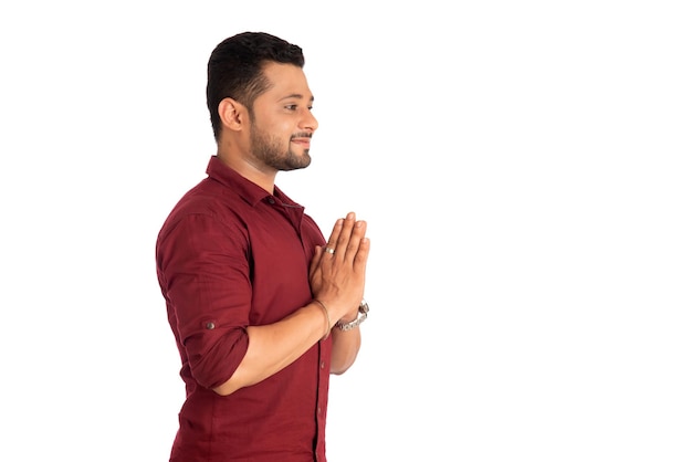 Joven indio con expresión de bienvenida o invitando o saludando a Namaste de fondo blanco