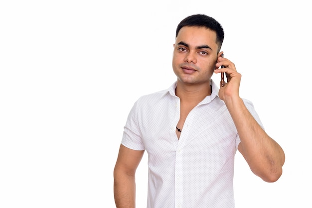 Joven indio guapo hablando por teléfono móvil aislado contra el espacio en blanco