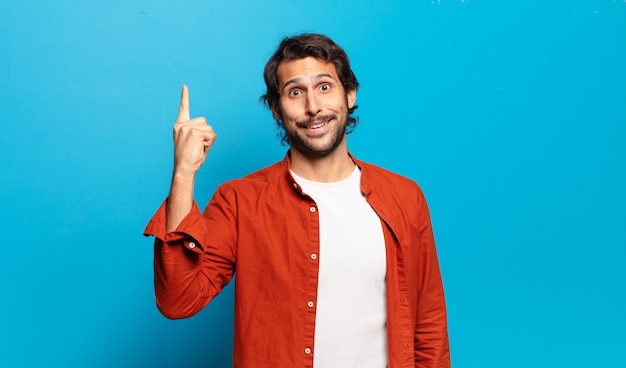 Foto joven indio guapo que se siente como un genio feliz y emocionado después de darse cuenta de una idea, levantando alegremente el dedo, ¡eureka!