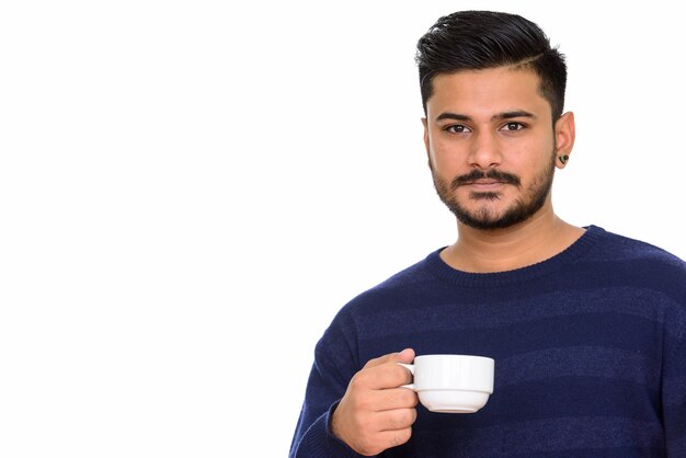 Joven indio guapo sosteniendo la taza de café