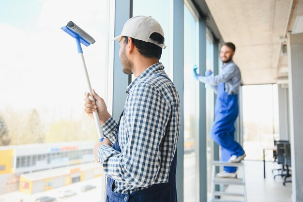 Joven indio lavando la ventana en la oficina