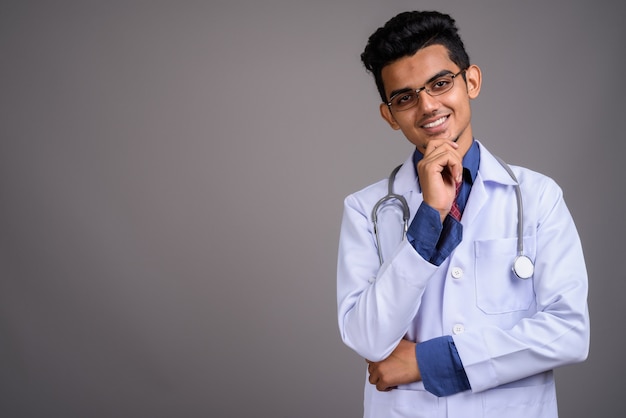 Joven indio médico contra la pared gris