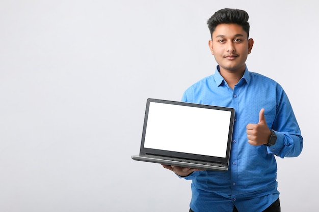 Joven indio mostrando la pantalla de un portátil con fondo blanco.