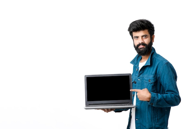 Joven indio mostrando la pantalla del portátil sobre fondo blanco.