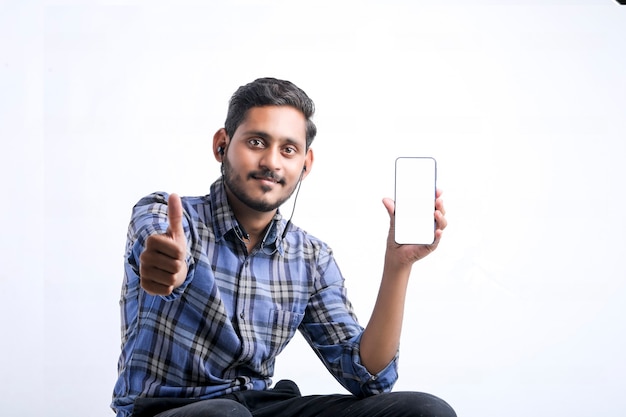 Joven indio mostrando Smartphone sobre fondo blanco.