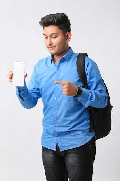 Joven indio que muestra la pantalla del teléfono inteligente con fondo blanco.