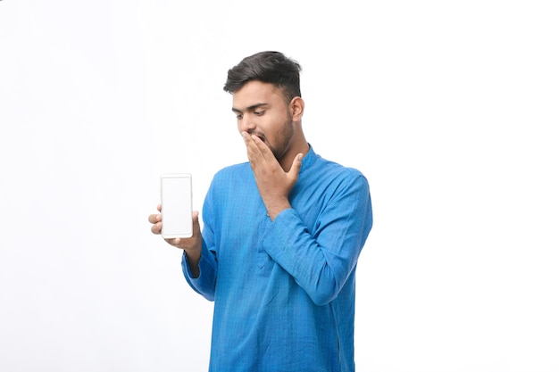 Joven indio en ropa tradicional y mostrando la pantalla del teléfono inteligente sobre fondo blanco.