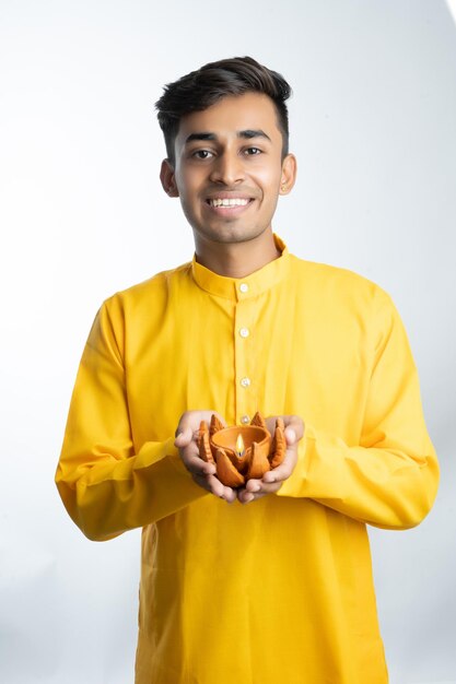 Joven indio sosteniendo Diya para Diwali y vistiendo ropa tradicional