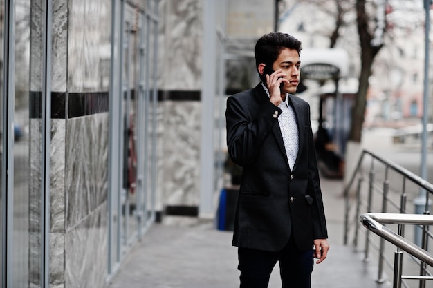 Joven indio en traje posó al aire libre hablando por teléfono