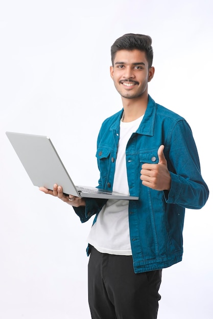 Joven indio usando laptop y mostrando golpes sobre fondo blanco.