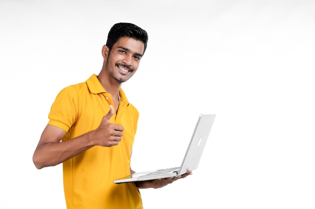 Joven indio usando laptop sobre fondo blanco.