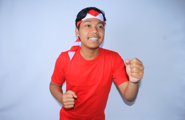 Un joven indonesio feliz hace una pose de carrera con una cara sonriente con una camiseta roja y una diadema