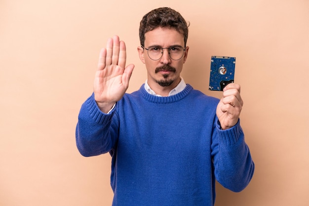 Joven informático aislado de fondo beige parado con la mano extendida mostrando la señal de alto, impidiéndote.