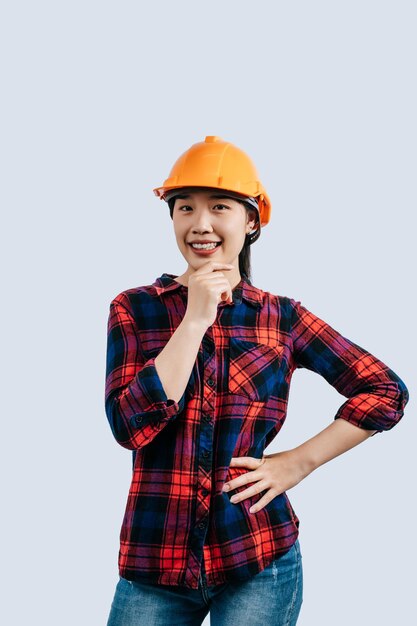 Joven ingeniera con casco amarillo y postura de sonrisa encantadora