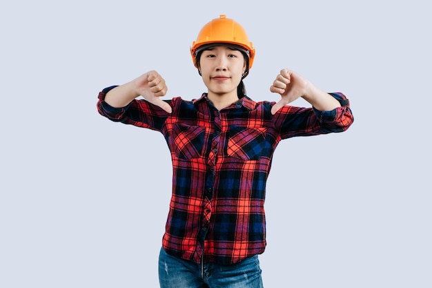 Joven ingeniera con casco de pie con el pulgar hacia arriba