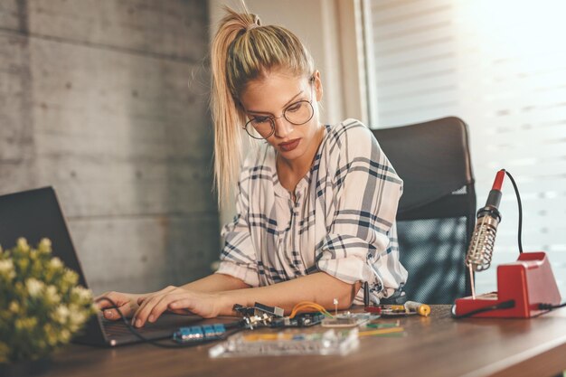 La joven ingeniera se centra en la reparación de equipos electrónicos y en comprobar algo en la computadora portátil.