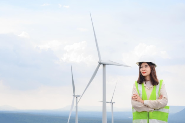 Una joven ingeniera trabaja en una planta de energía eléctrica renovable en un campo de molinos de viento que produce energía eléctrica