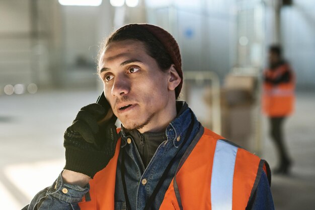 Foto joven ingeniero confiado en ropa de trabajo hablando por teléfono móvil