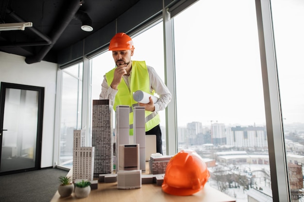 Joven ingeniero constructor con casco trabajando en la construcción de un proyecto prototipo complejo