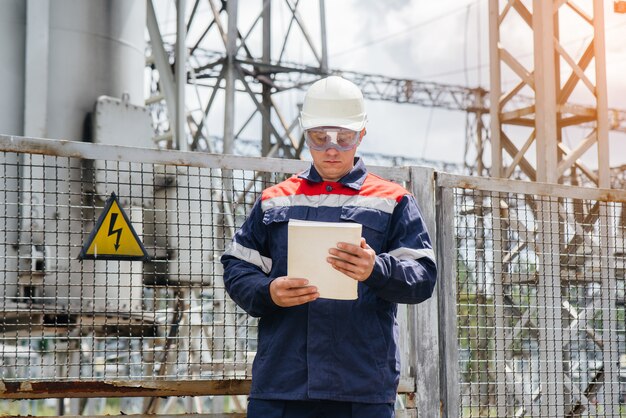 Un joven ingeniero se encuentra en una máscara en una subestación eléctrica.