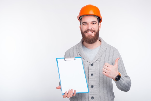 El joven ingeniero está apuntando a un tablero de papel con papeles en blanco que son buenos para su texto