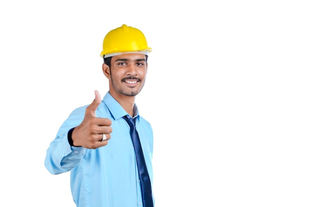 Joven ingeniero indio con casco de color amarillo y dando un gesto exitoso.