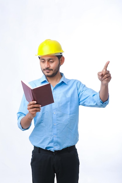 Joven ingeniero indio con casco y viendo el diario