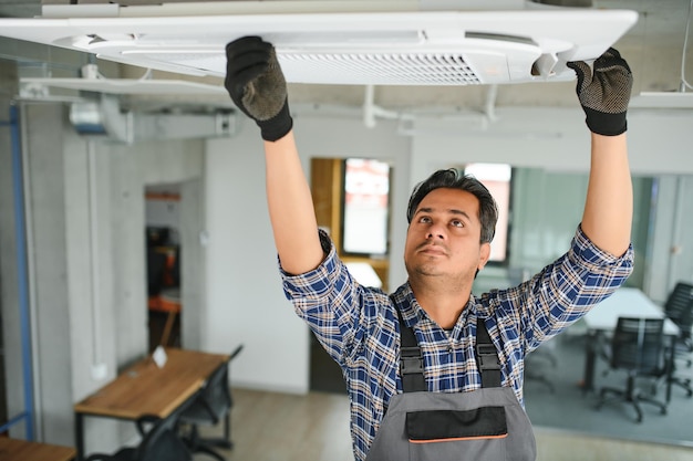 Un joven ingeniero indio concentrado instalando un aire acondicionado
