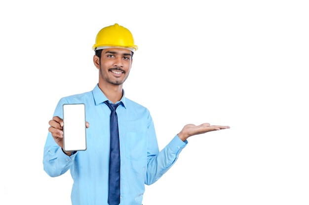 Joven ingeniero indio o trabajador de la construcción que muestra la pantalla del teléfono inteligente.