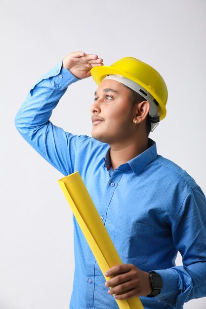 Joven ingeniero indio con sombrero duro de color amarillo y dando un gesto exitoso.