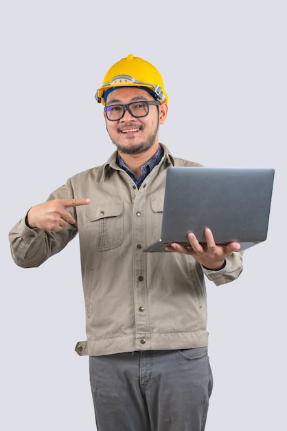 Joven ingeniero informático hombre asiático con portátil y casco amarillo