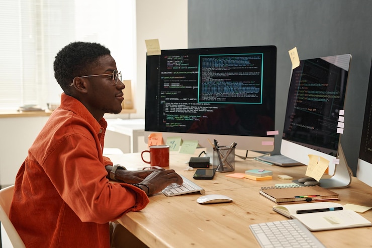Foto joven ingeniero informático serio con camisa naranja inteligente mirando datos codificados