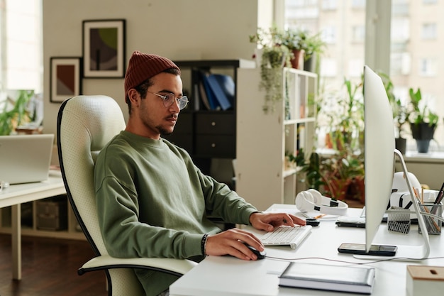 Joven ingeniero de soporte de TI serio mirando la pantalla de la computadora