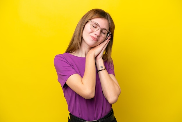 Joven inglesa aislada de fondo amarillo haciendo gestos de sueño con una expresión adorable