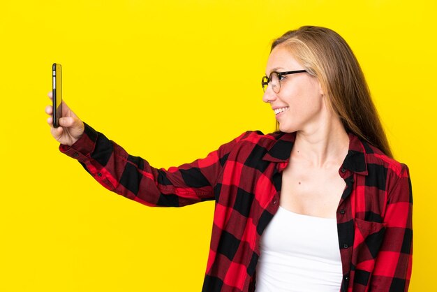 Joven inglesa aislada de fondo amarillo haciendo un selfie