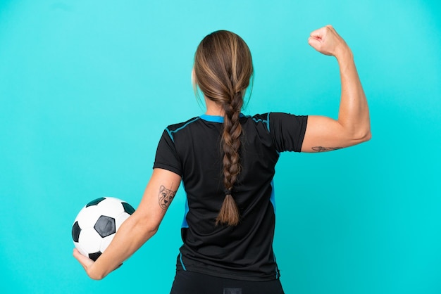 Joven inglesa aislada de fondo azul con balón de fútbol