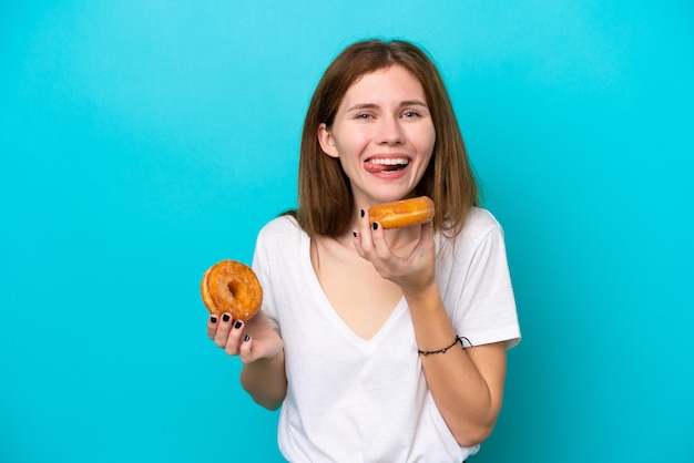 Joven inglesa aislada de fondo azul sosteniendo un donut