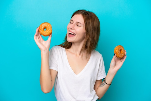 Joven inglesa aislada de fondo azul sosteniendo donuts con expresión feliz